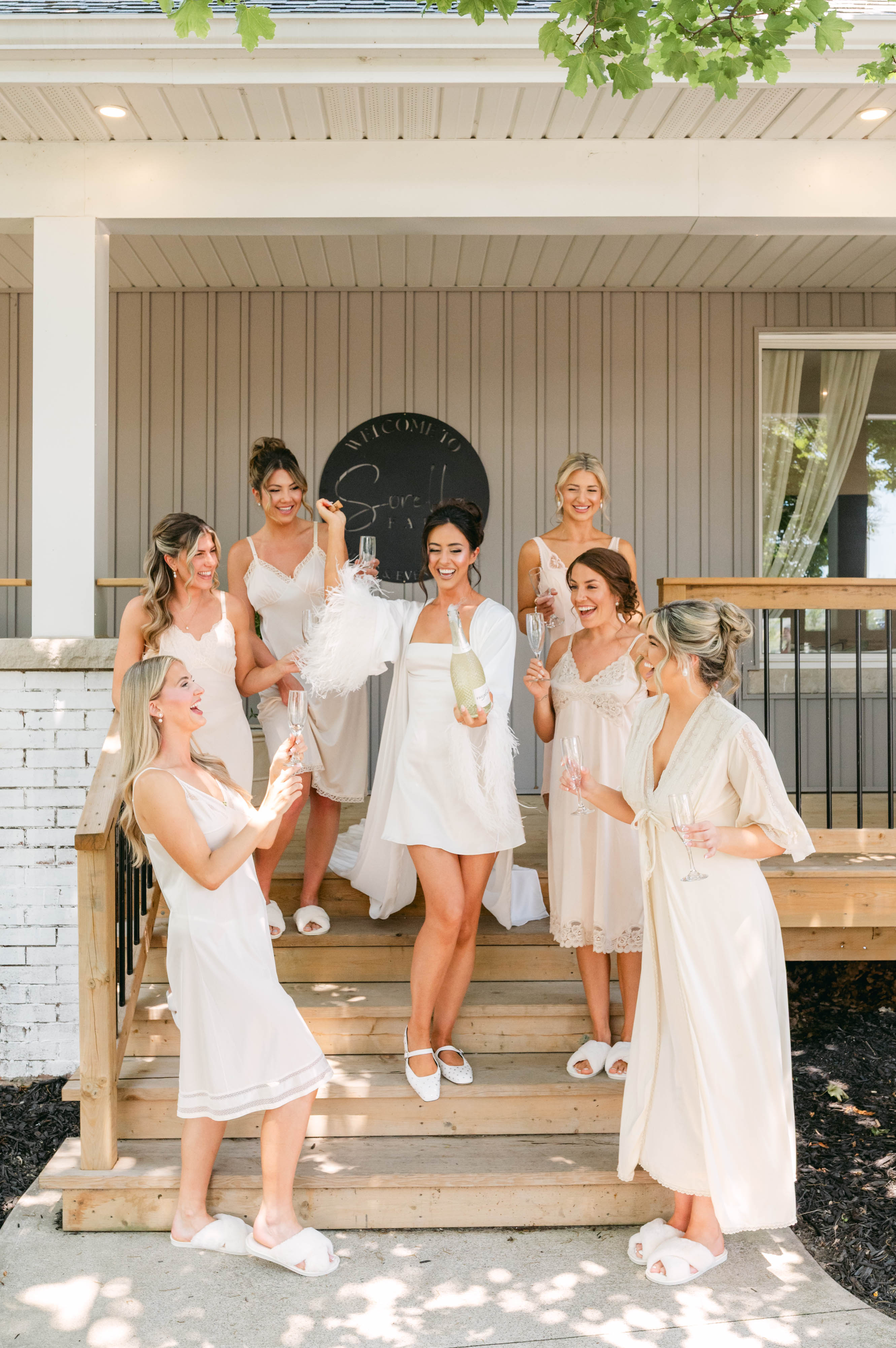 Bridal party in silk robes on the Ranch House porch at Sorella 1881, sharing a champagne toast