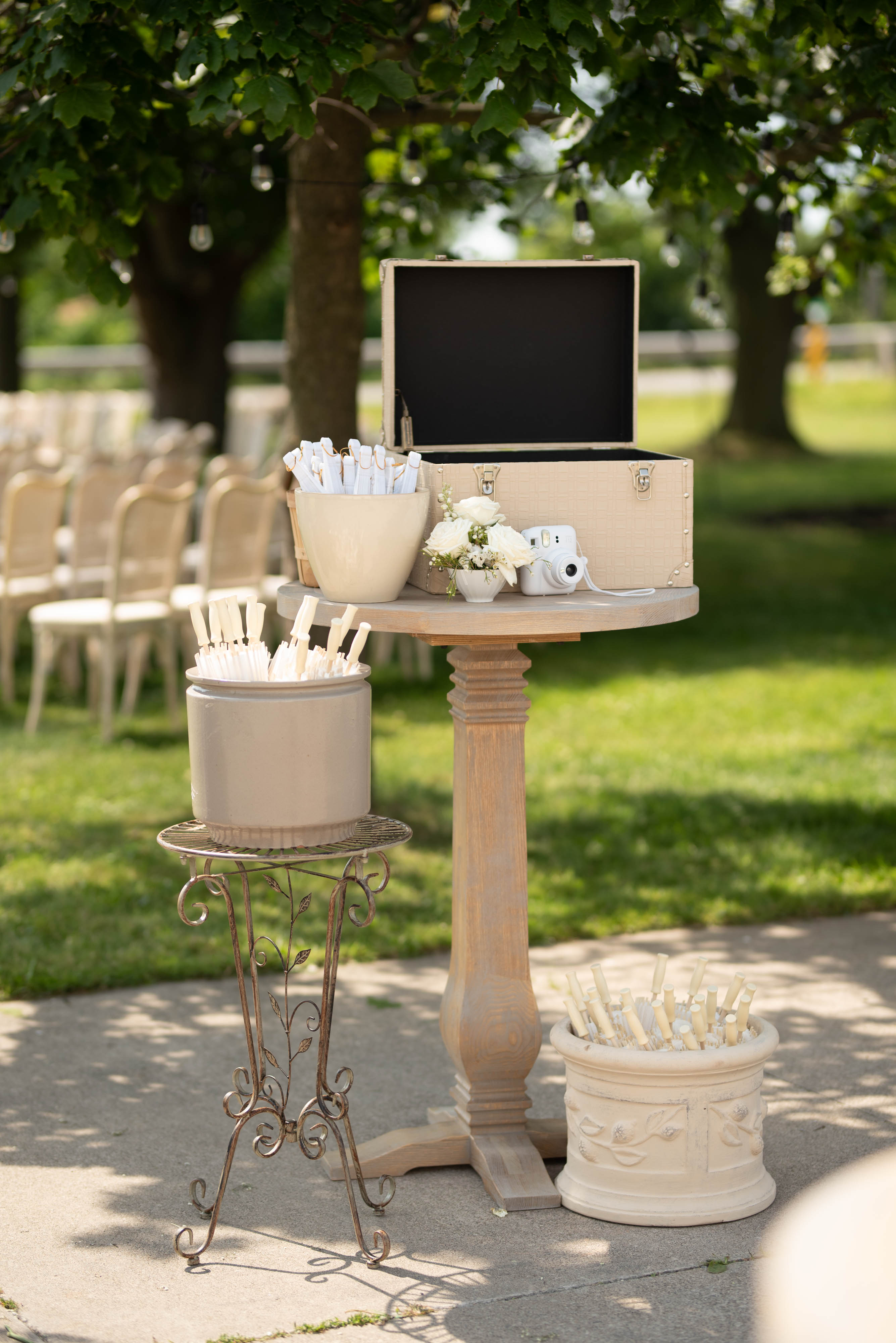 Ceremony programs displayed in a vintage trunk with a Polaroid camera and floral accent