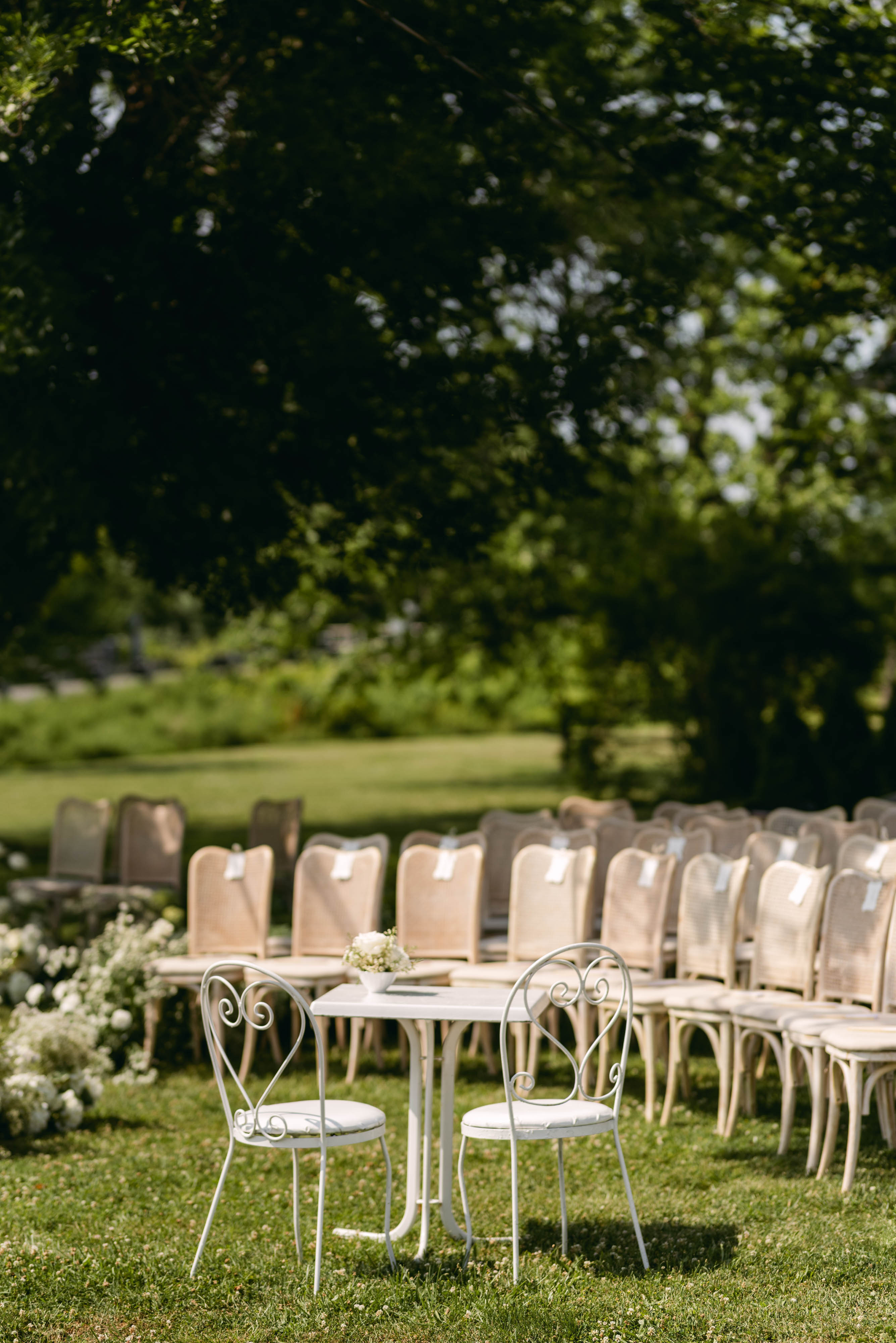 Intimate signing table with two heart-back chairs and florals at the head of the ceremony aisle
