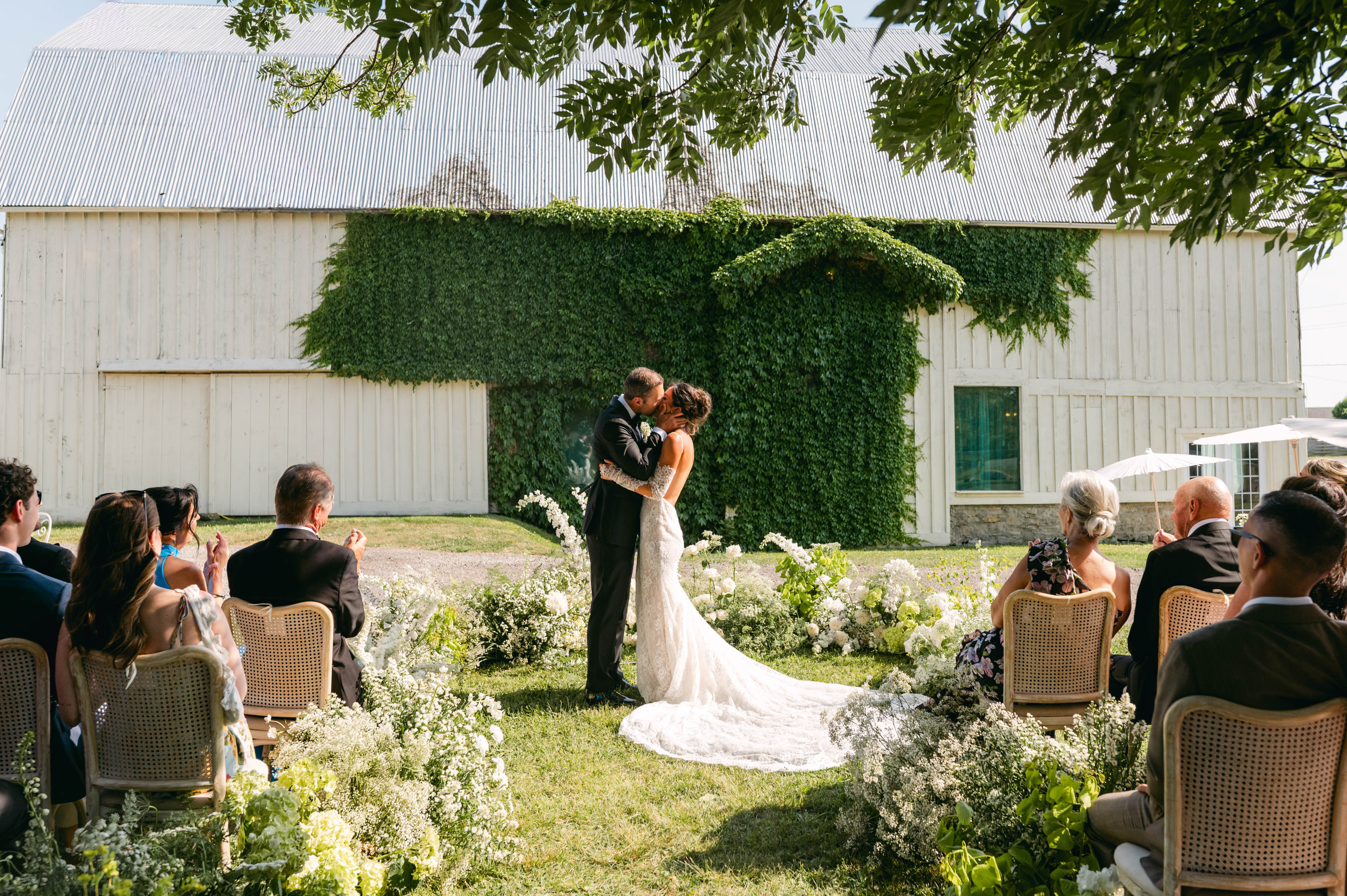 Bride and groom's first kiss at the ivy-covered 1881 barn during their ceremony