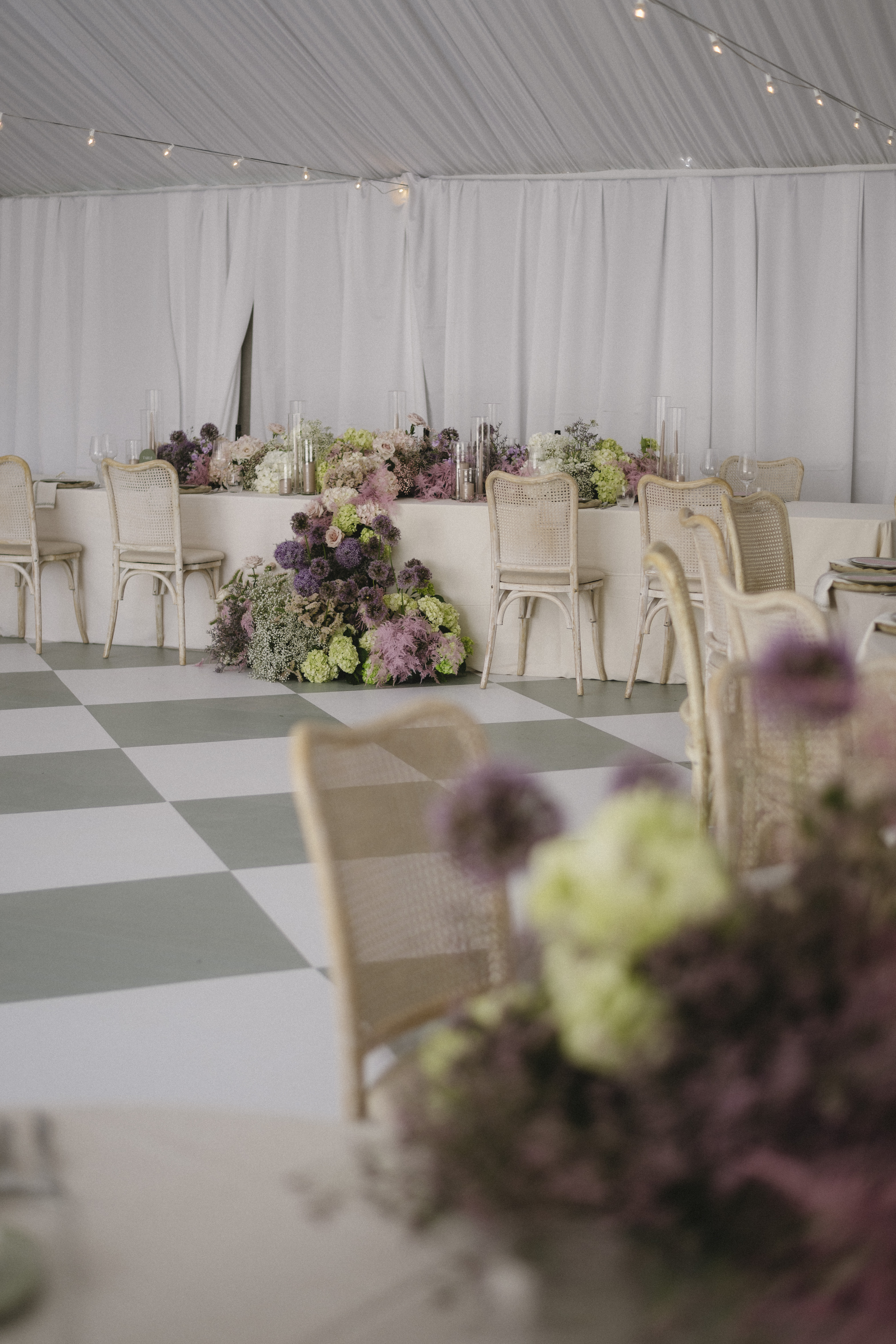 Head table in the Blanc Marquee dressed with lavender and cream florals, cane chairs, and taper candles