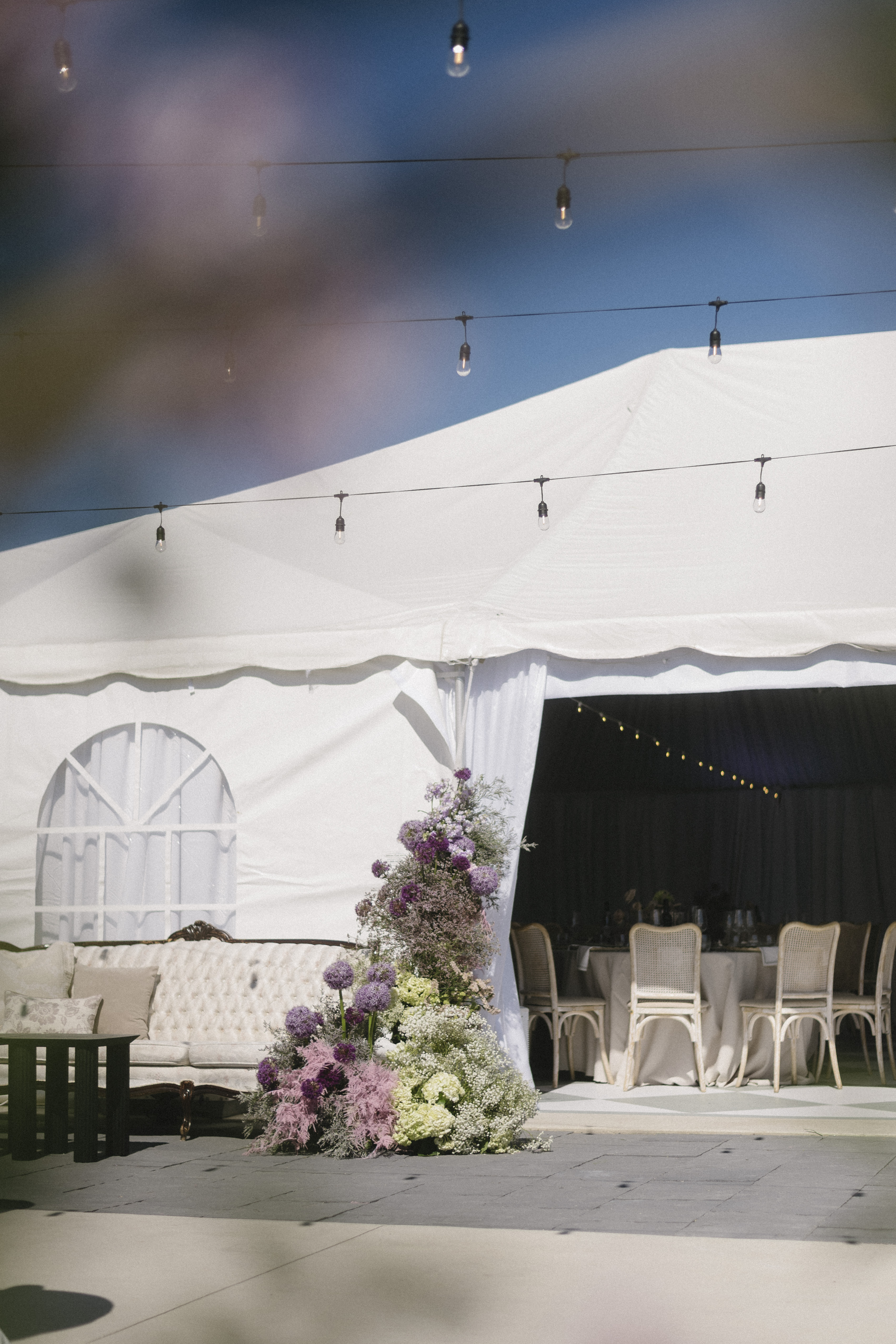 Blanc Marquee cocktail lounge with cascading lavender florals and a tufted white sofa