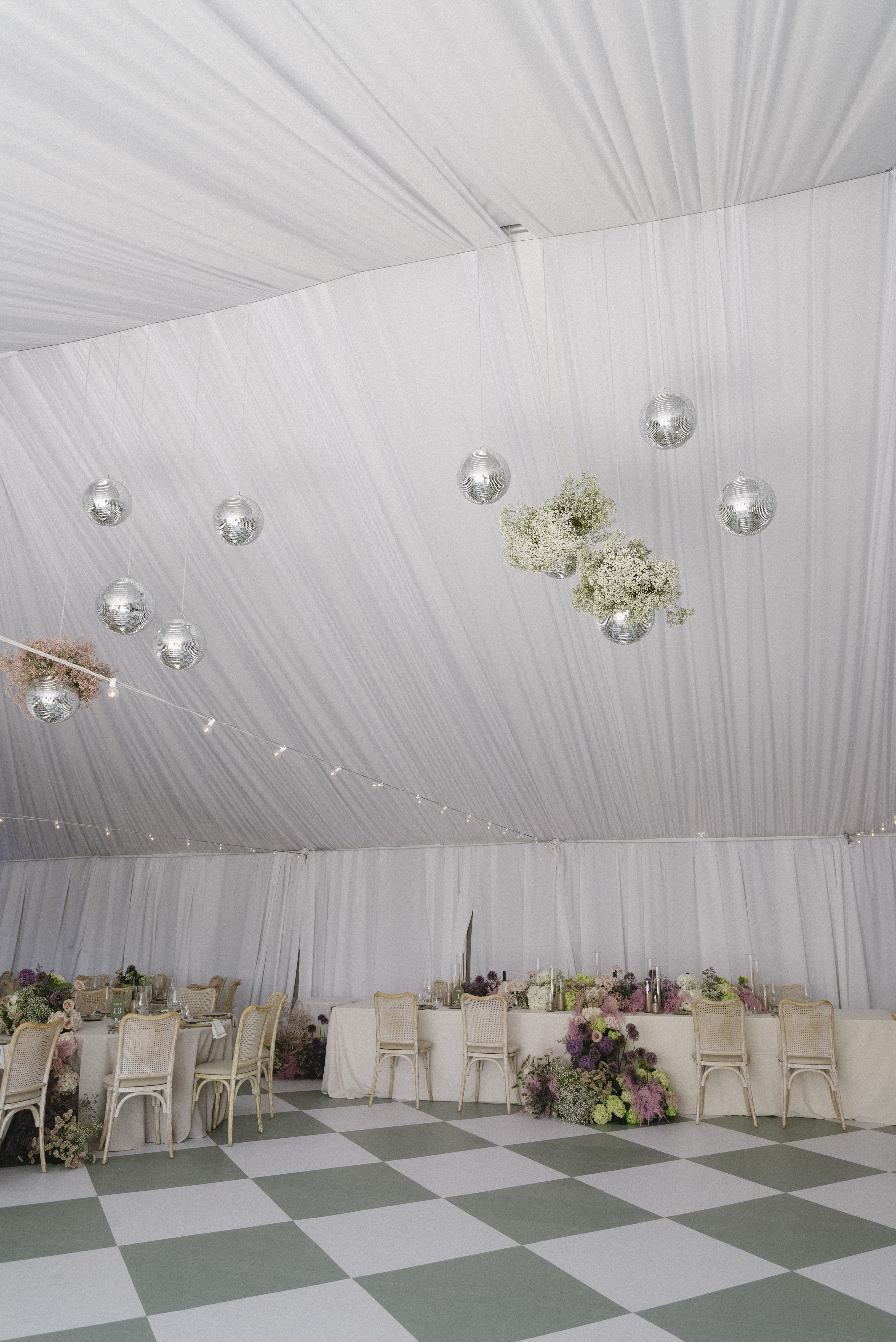 Interior of the Blanc Marquee at Sorella 1881 — draped white canopy, disco balls, and floral centrepieces above the checkered dance floor