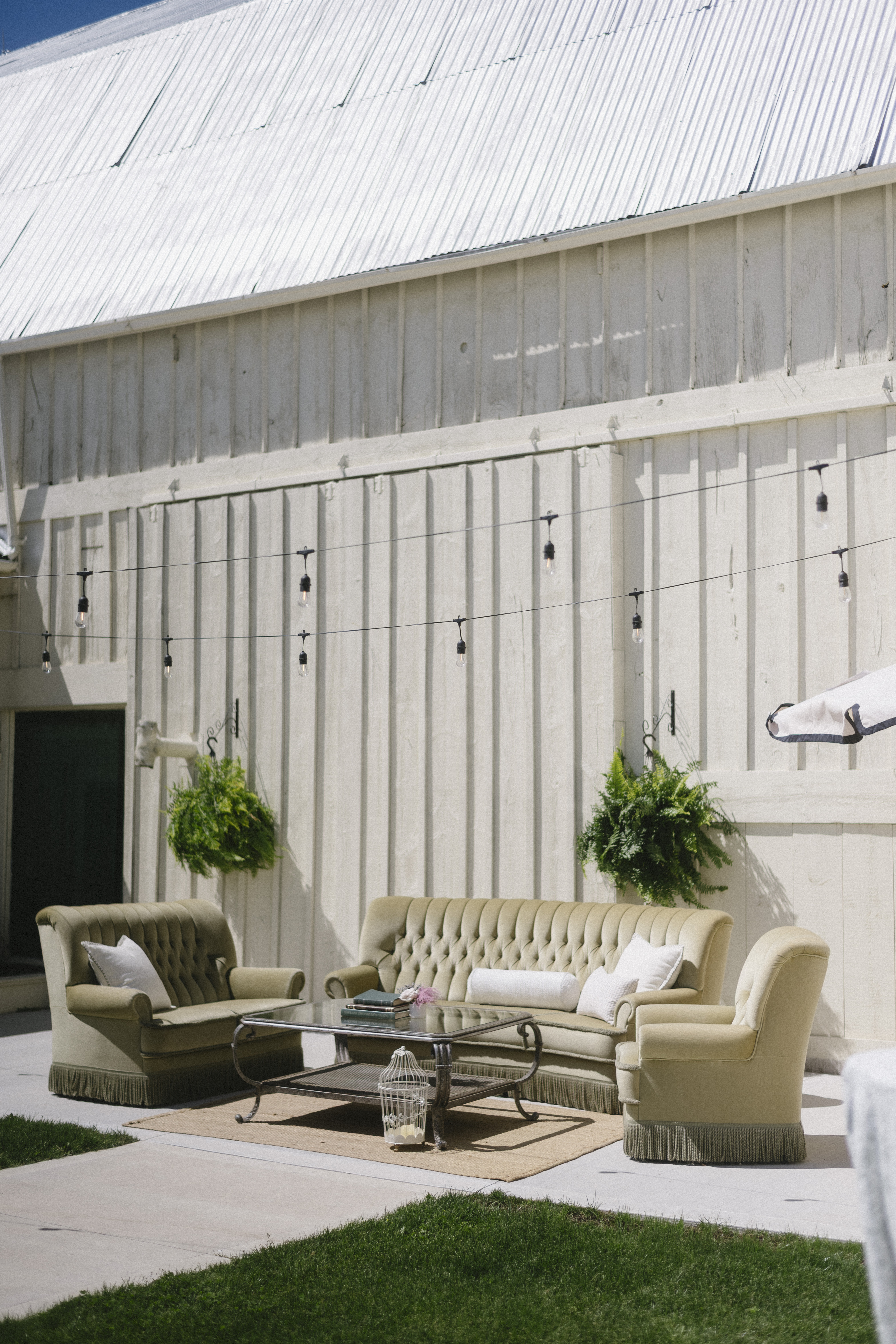 Estate lounge area — vintage tan sofas beneath the historic barn with hanging ferns at Sorella 1881