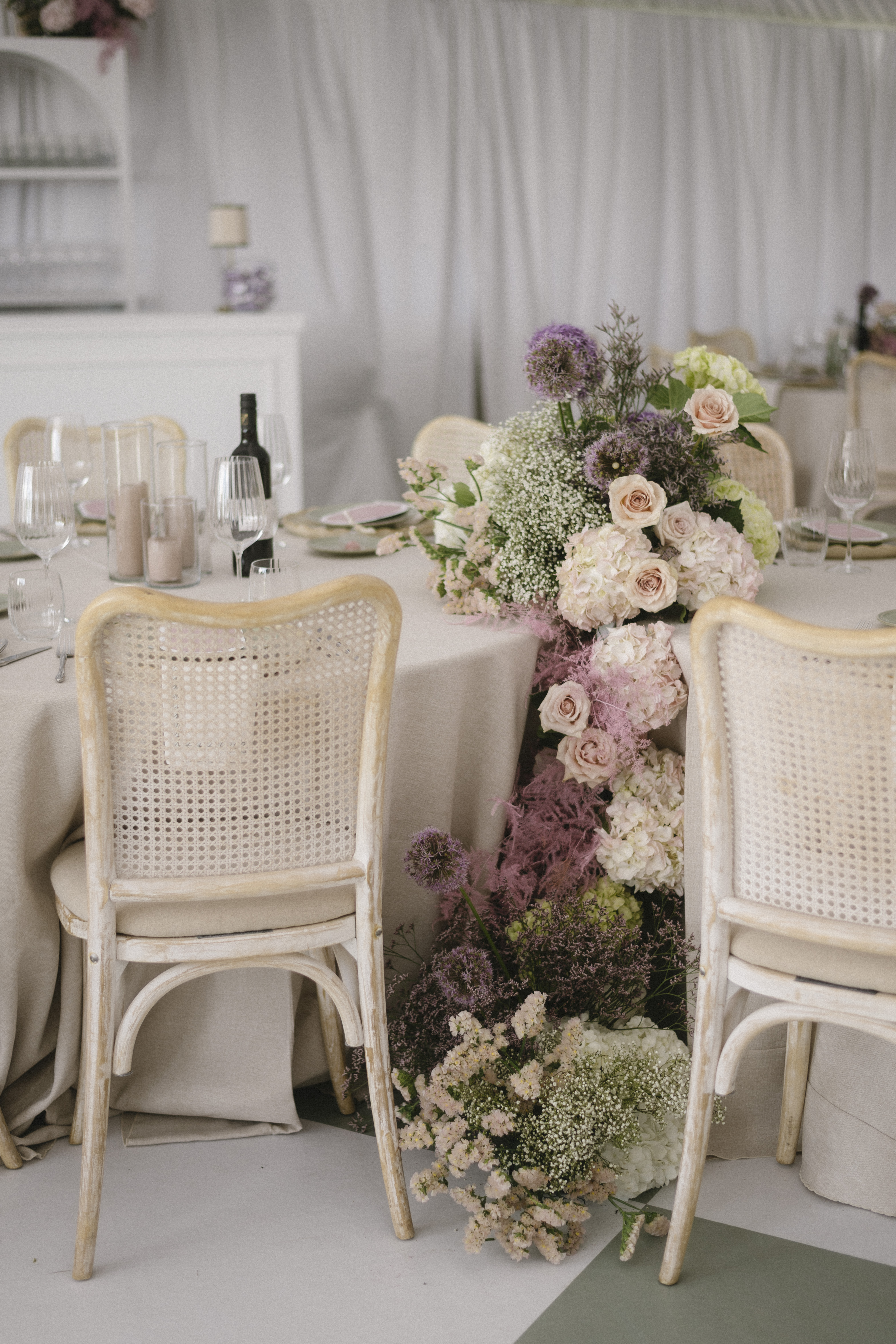 Head table with cascading floral runner of dahlias, roses, and thistle inside the Blanc Marquee