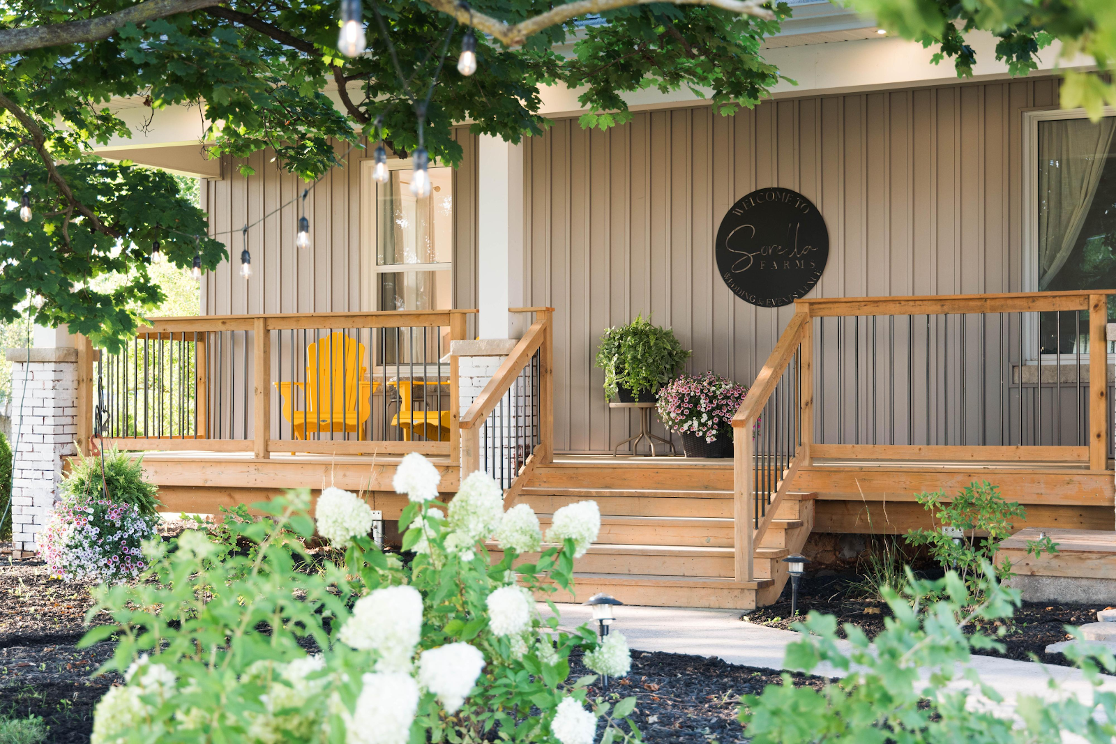 Exterior of Sorella Farms farmhouse with circular sign on wood-panelled facade, surrounded by hydrangeas