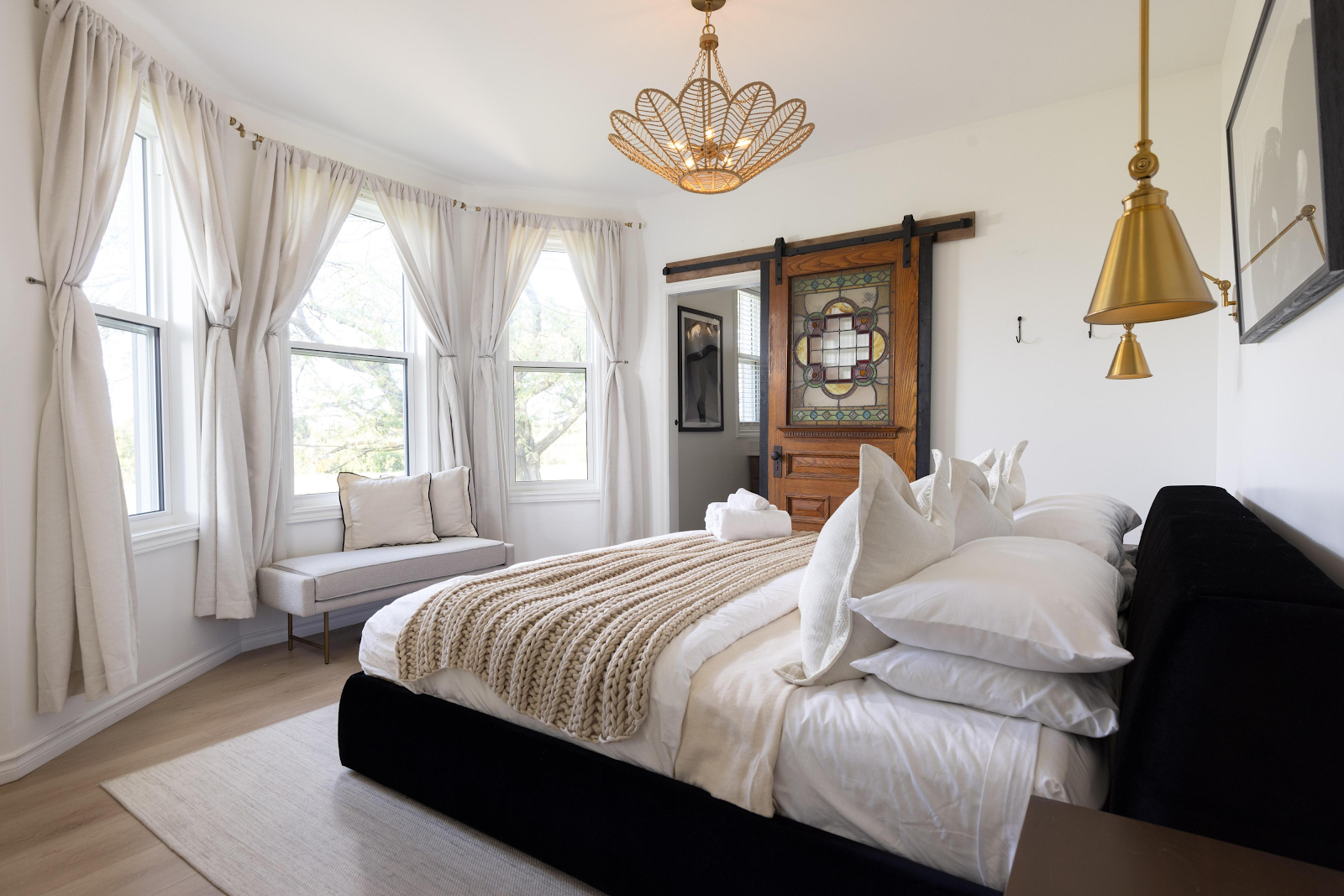 Master bedroom in The Ranch House at Sorella 1881 — luxury bed, bay windows, gold pendant lights