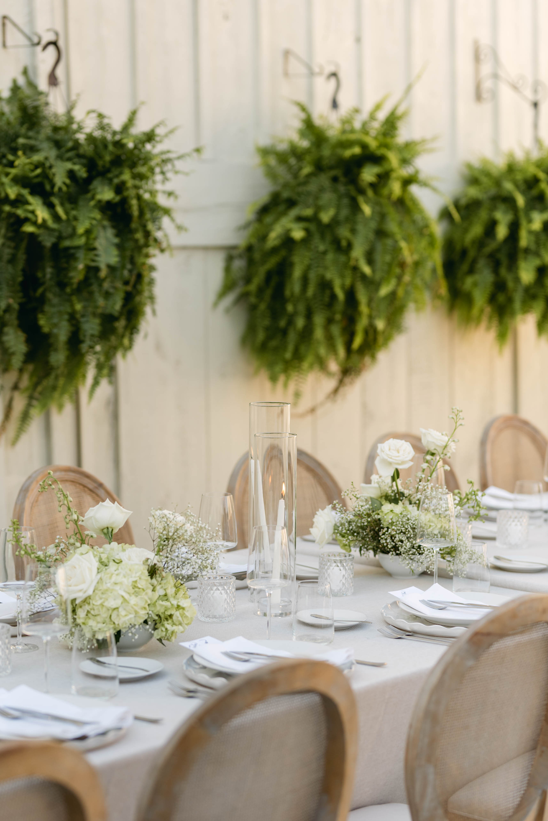 Elegant wedding tablescape at Sorella 1881 — white floral centrepieces against hanging fern wall